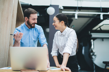 Cheerful adult employees looking at each other while having discussion in office