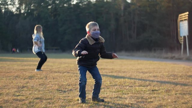 Quarantine Covid-2019 coronavirus. Female mom and child boy kid with protective medical mask performs physical exercises sports outdoor. Strengthening the body immunity 