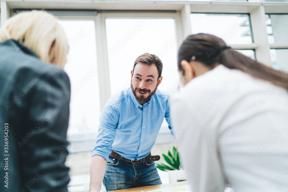 Wall mural Positive man sharing ideas with female colleagues at workplace