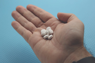 Hand holding white opioid pills. Drug addiction concept image. 