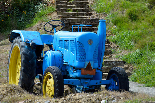Vintage old blue and yellow tractor on the street of a small village in Spain