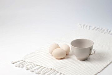 white Cup and homemade eggs on a white cotton napkin with tassels