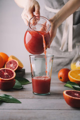 Female hands pouring juice from red oranges. Freshly squeezed juice from variety of oranges