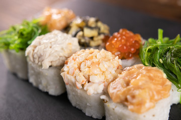 Rolls with a cap of seaweed, red caviar, shiitake mushrooms, shrimp, mussels in sauce, close up
