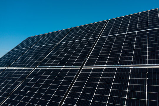 Background of photovoltaic modules for renewable energy. Huge solar panels with clear blue sky.