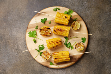 Grilled sweet corn served with pepper and herbs. Food background, copy space