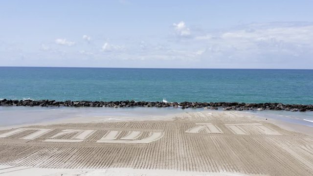 Happy Holiday in Hebrew letters written in Sand on a beach, Aerial view.