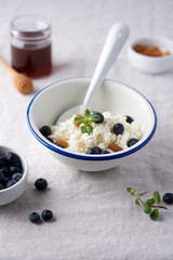 Fresh cottage cheese in bowl for breakfast. Gray tablecloth background