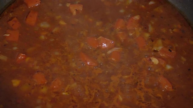 Cooking tomato sauce to prepare spaghetti with meatballs