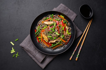 Stir fry noodles with vegetables and soy sauce. Asian food background. Black stone background