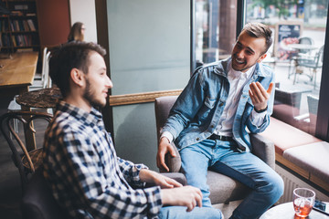 Pleased adult males friends having conversation in cafe