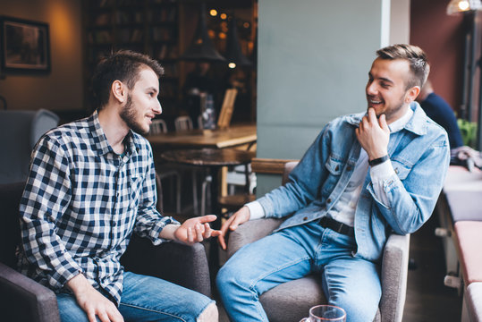 Cheerful young modern men having conversation in cafe