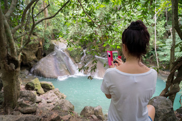 young cute hipster girl travelling at beautiful Erawan waterfall mountains 
green forest hiking views at Kanchanaburi, Thailand. guiding 
idea for female backpacker woman women backpacking