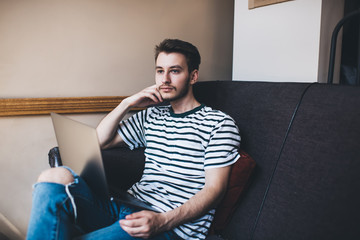 Thoughtful man working on laptop and thinking leaning on hand