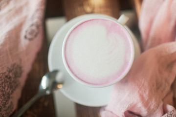 Pink tea matcha in a white mug on the table.
