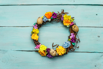 Hand crafted Easter wicker wreath with quail eggs and handmade flowers. Birch branches, polka dot satin ribbon. Stay at home concept. Festive Easter background