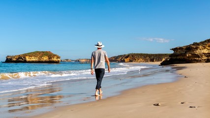 Senior Man walking barefoot on bay of Islands beach Victoria Australia near the great ocean road.
