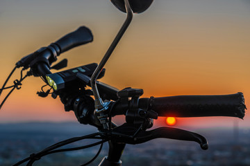 Fototapeta na wymiar Handlebar mirror and light on electric bike in sunset color evening