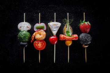 Image of Canape with cheese, strawberries, prawns, mushrooms, cherry tomatoes and olives on wooden sticks on a black table. Catering. Banquet. printed on Printed Glass Basin Splashbacks