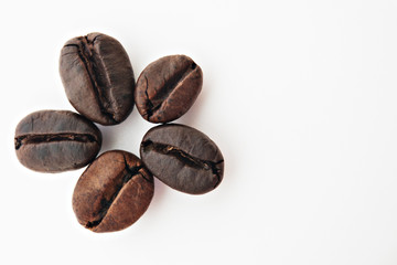 Shiny freshly roasted coffee beans folded in the form of a flower on a white background. Isolated
