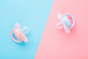 Two silicone baby soothers. Pastel pink blue table background. Closeup. First girls and boys toy. Top down view.