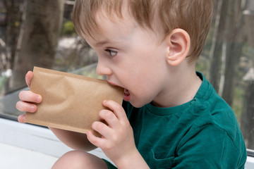 child nibbles a craft envelope with seeds. close-up portrait
