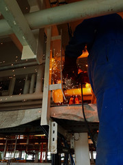 Welder welding steel angle bars for piping installation onboard a ship