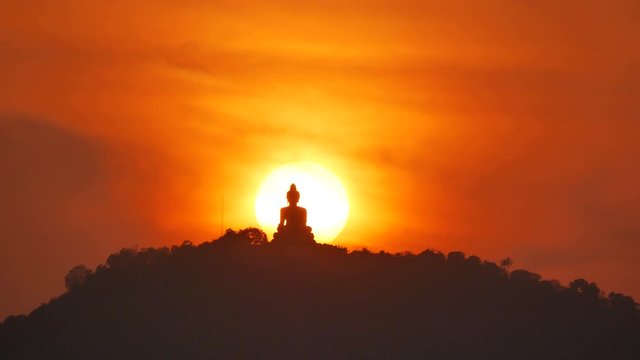 hue sunset behind Phuket buddha statue on hilltop mountain with many silhouette leaves trees, beautiful golden twilight sky background in evening time