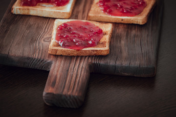 Toast anointed with jam on a wooden board
