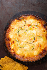 Homemade Roasted vegetable quiche. Easy sweet potato zucchini pie tart on rustic dark surface, copy space, top view. Healthy food concept. French cuisine.