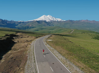 Man Riding on skateboard on Road to Elbrus, Highest Mount in Europe. Aerial Shot.