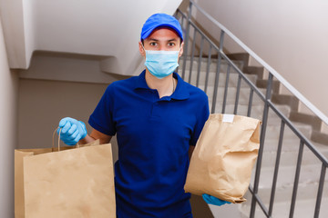 Fototapeta na wymiar Courier in protective mask and medical gloves delivers takeaway food. Delivery service under quarantine, disease outbreak, coronavirus covid-19 pandemic conditions.