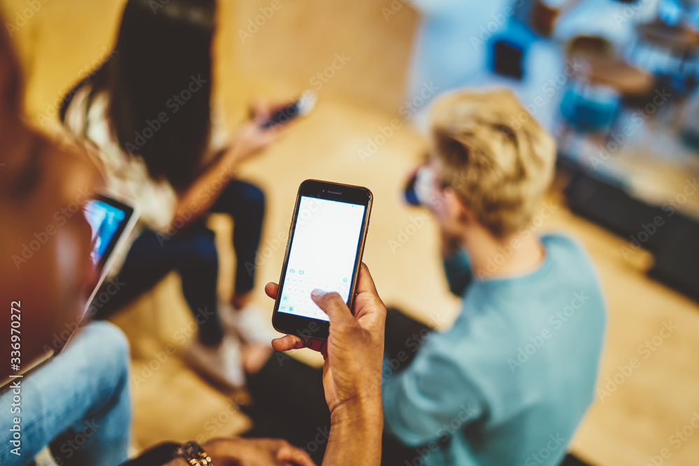 Poster cropped image of male holding modern smartphone with mock up screen texting message in chatting app,