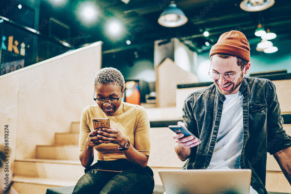 Poster prosperous generation z sharing media files and laughing during internet networking via mobile phone