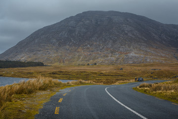 Lonely tourist with car left on a road in Connemara national park. Lost the way at the foot of the mountain