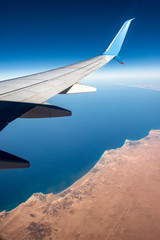 Fototapeta na wymiar Sahara desert and Mediterranean Sea seen from the plane with the aircraft wing, north coast of Egypt, El Alamein, Matrouh Governorate, Africa