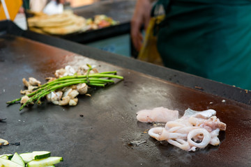 Cheff preparing traditional Mediterranean squid dish on a hot grill.