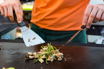 Cheff preparing traditional Mediterranean squid dish on a hot grill.