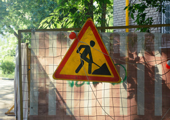 Shabby road sign with digging man. Shot with a backlight