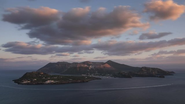 Time lapse of Italian island Vulcano during sunset, boats moving in the sea, clouds in the sky, Liparic Islands Sicily
