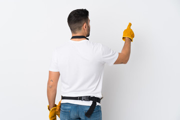 Craftsmen or electrician man over isolated white background pointing back with the index finger