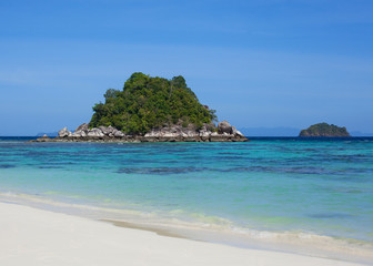 Fototapeta na wymiar View on an uninhabited island in blue lagoon from white sand beach