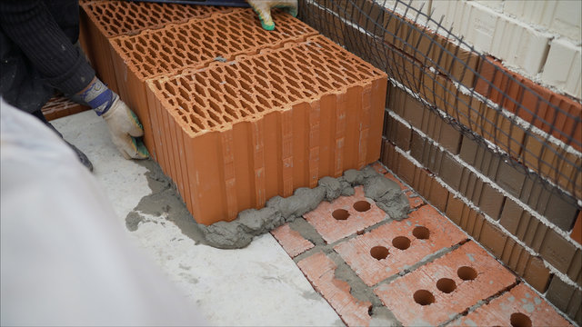 Laying red ceramic blocks at a construction site. CERAMIC BLOCKS FOR BUILDING A HOUSE. Warm ceramics: features and specifications. Building a house from a red ceramic block. Stock footage. Block