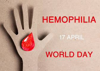 Hemophilia World Day background. Silhouette of a hand with a drop of blood on a cardboard...