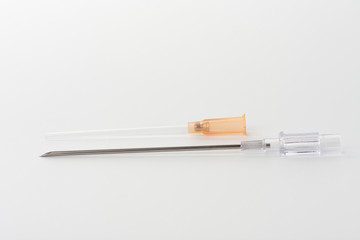 Orange intravenous cannula 14 G on white background, external diameter 2,1 mm, used in trauma, blood transfusion, surgery, ascites puncture.