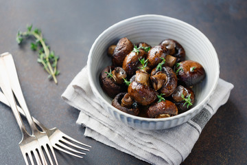 Grilled champignons with thyme in a ceramic bowl. Simple taste recipe.