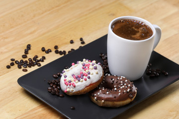 White coffee cup on a wooden table with chocolate and white chocolate donuts . Morning espresso. Morning cappuccino mug. 