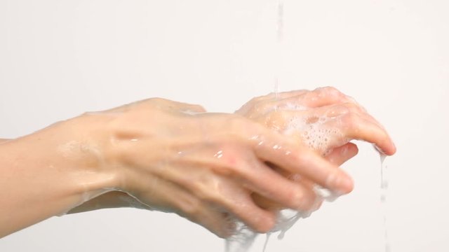 Caucasian woman washing her hands under running water isolated on white background