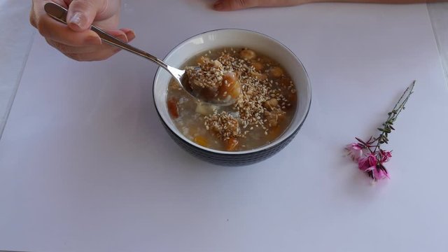 Woman eating Ashure aka Turkish Noah's Pudding served with bowl and spoon.