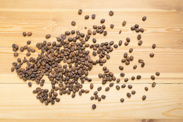 Roasted coffee beans randomly dumped on a wooden table